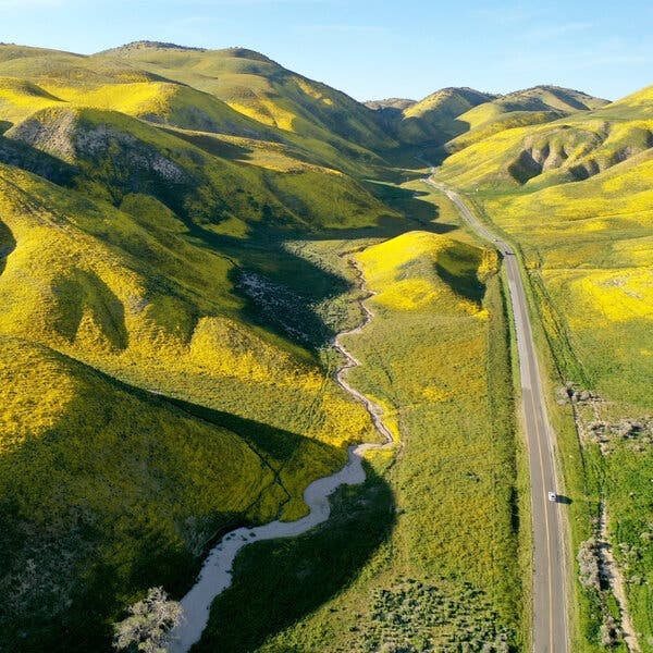 An aerial view of a road cutting through rolling green hills. 