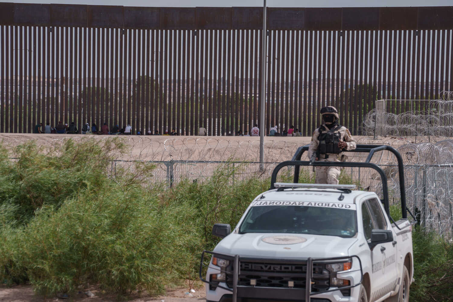 Migrants rested in the shade of the border wall between the United States and Juárez, Mexico.