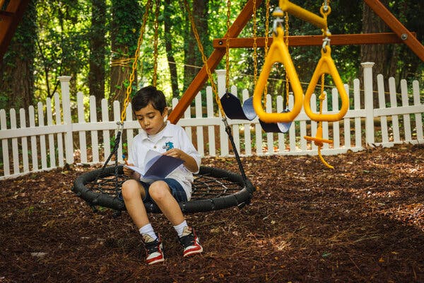 Nathanael sits on a large circular swing, holding a journal. 