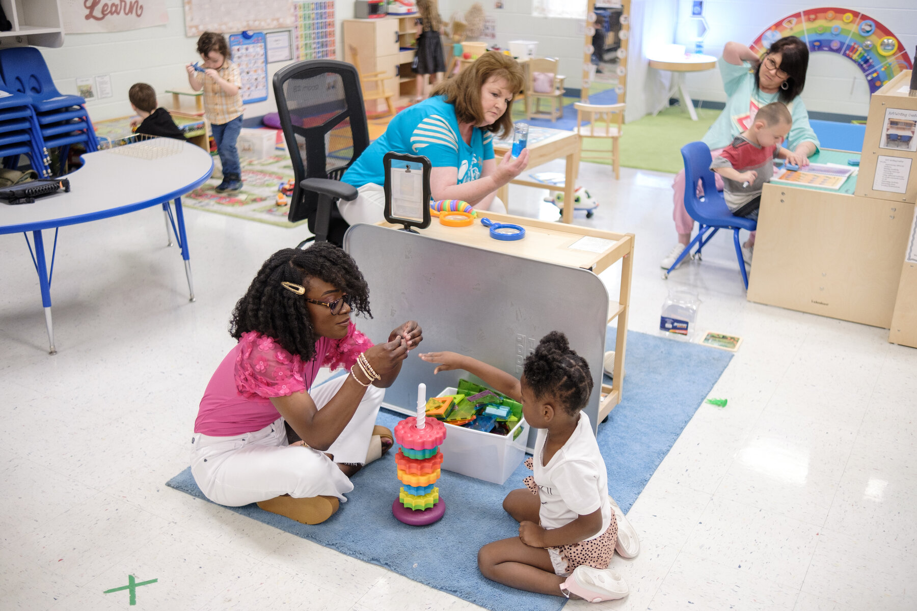 Michaela Frederick, a preschool teacher, plays with a stacking toy with a student.