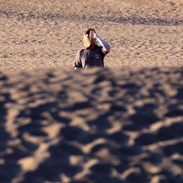 A tourist drinking water as he hikes in the dunes.