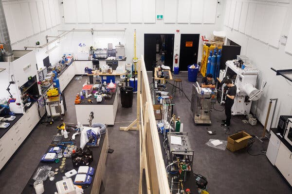 An overhead view of a large laboratory, with work spaces crowded with equipment and experiments in progress.