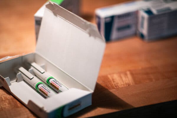 A close-up view of an open box of Toujeo injector pens on a wooden table.