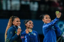 From left, Rebeca Andrade of Brazil and Simone Biles and Sunisa Lee of the United States taking a selfie together after winning medals in the individual all-around final for artistic gymnastics during the Paris Games.