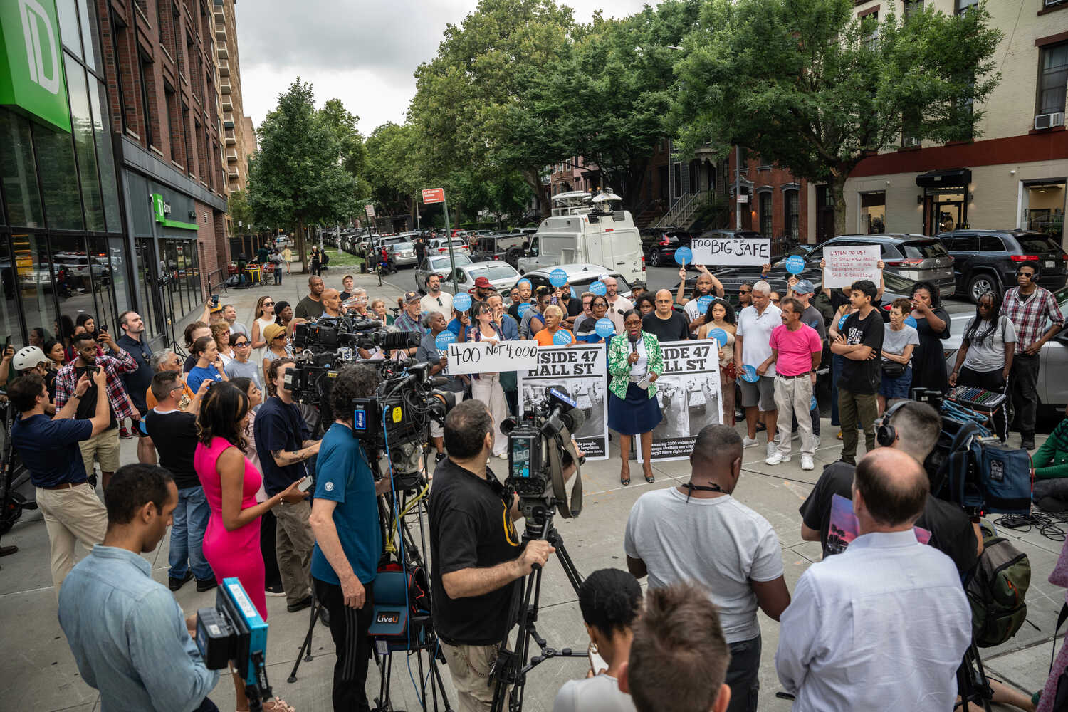 The killings of two migrants outside a large Brooklyn shelter prompted some residents to hold a rally to protest the shelter’s size.