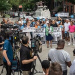 The killings of two migrants outside a large Brooklyn shelter prompted some residents to hold a rally to protest the shelter’s size.