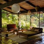 In the great room of Amy Pascal and Bernard Weinraub’s Los Angeles home, a 1955 Joseph-André Motte rattan daybed from Galerie Half and a 1957 Arflex sofa by Marco Zanuso, which is flanked by a Verner Panton shell light and a 1954 brass floor lamp by Philip Johnson and Richard Kelly. The decoupage coffee table was inherited from Pascal’s mother, Barbara Pascal, and the vintage rope chair is by Dan Johnson.