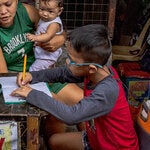 Extreme heat in May closed some schools in the Philippines. Students did schoolwork near a Manila storefront.