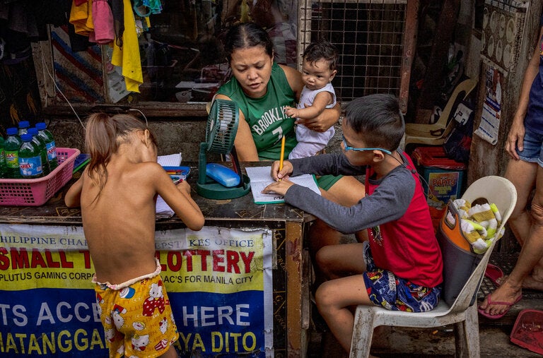 Extreme heat in May closed some schools in the Philippines. Students did schoolwork near a Manila storefront.