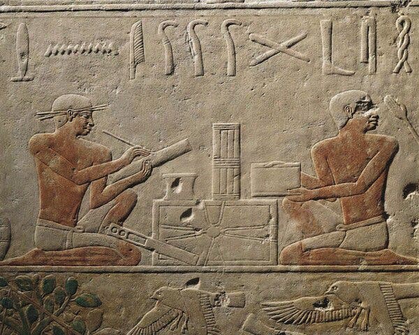 Two kneeling scribes depicted on a stone relief from ancient Egypt.