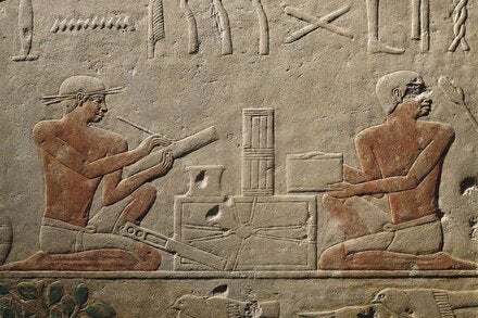 Two scribes in a relief from the Tomb of Akhethotep in Saqqara, Egypt. Scribes performed vital administrative functions, such as drawing up contracts and measuring fields for tax purposes.