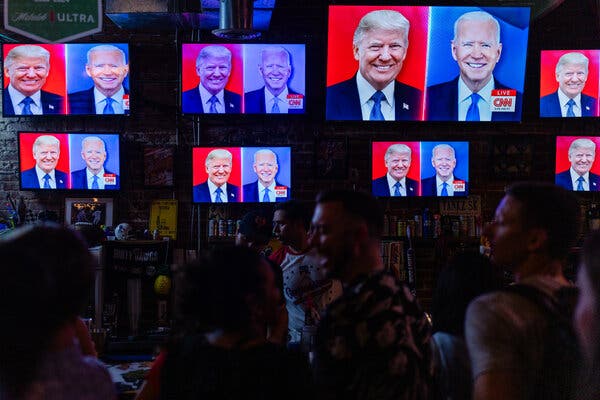 People watch screens showing President Biden and former President Donald J. Trump on TVs at a bar.