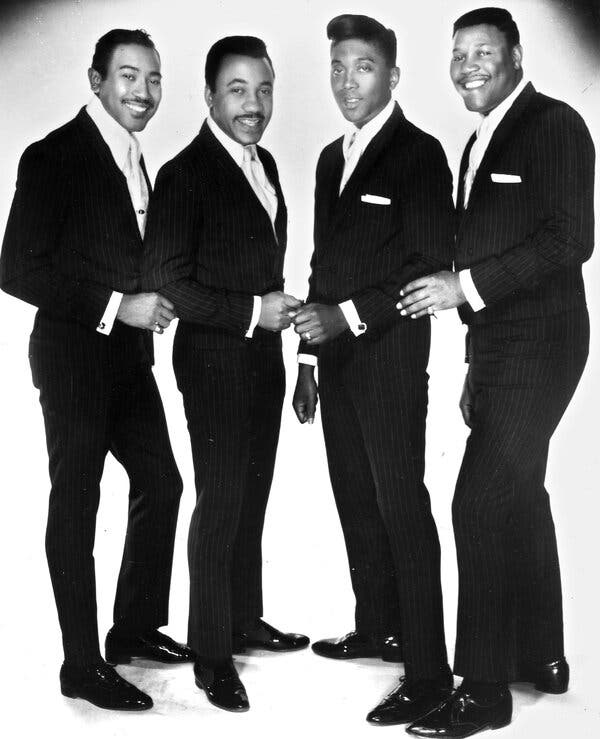 Maurice Williams and four other men in a black-and-white publicity photo. They are all wearing pinstriped suits and look as though they are about to start singing.