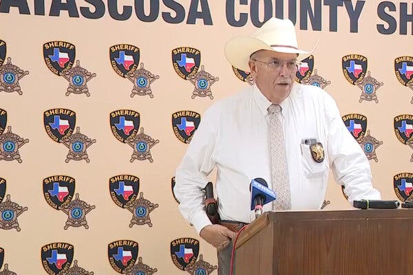 Sheriff David Soward, wearing a cowboy, stands at a lectern during a news conference.