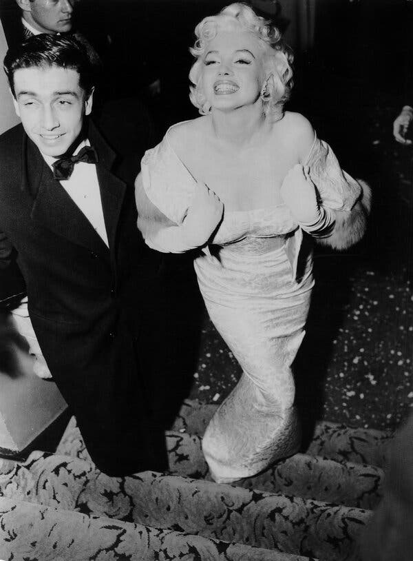 A black-and-white photo of Jay Kanter, a formally dressed young man, with Marilyn Monroe, who wears a low-cut dress and smiles broadly.