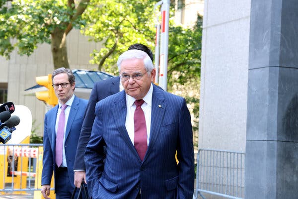 Senator Robert Menendez, wearing a blue suit and red tie, outside a federal courthouse.