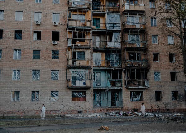 A large building with blown-out windows and piles of debris around it.