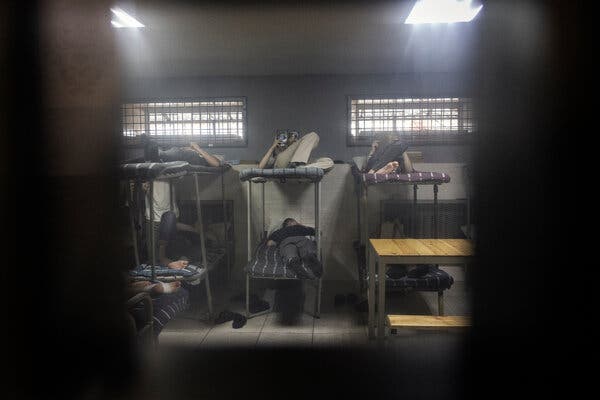 People lying down on metal bunk beds.