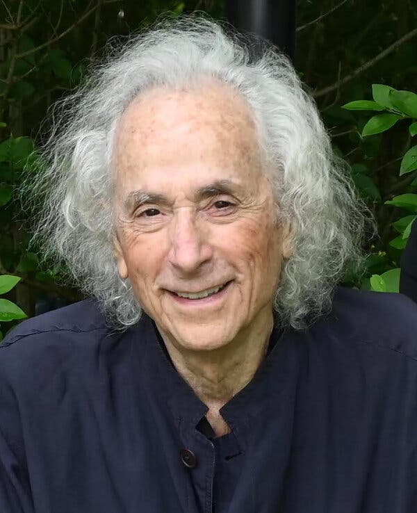 A close-up portrait, taken outdoors, of Charlie Moss, a smiling man with long white hair.