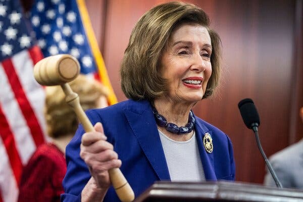 Representative Nancy Pelosi holds up a gavel (the one she used when the Affordable Care Act was passed), with an American flag in the background. 