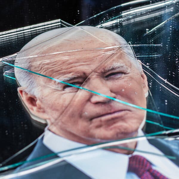 A headshot of Joe Biden lies beneath broken glass.