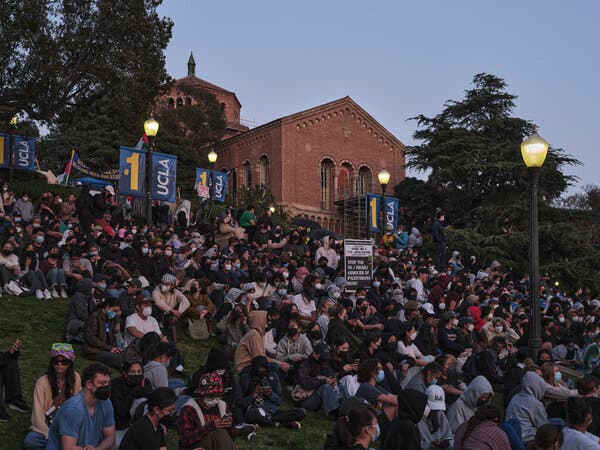 Hundreds of student protesters sitting outside at U.C.L.A., some wearing masks.