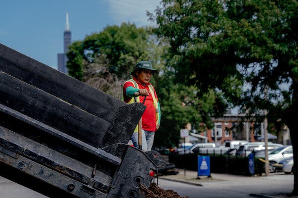 A worker stood beside a piece of heavy equipment as part of Chicago’s skyline was visible behind him.