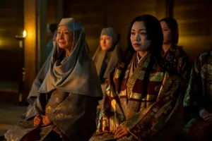 Four women wearing traditional Japanese 17th century attire sit in a candlelit room.