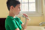 A child brushing their teeth with an electric toothbrush.