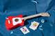 A Loog Mini Acoustic Guitar, shown on a blue paper background.