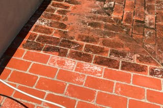 A brick patio that has been partially pressure washed.