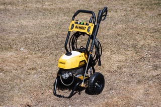 The yellow and black DeWalt DWPW2400 2400 PSI Electric Cold-Water Pressure Washer, our runner up for best pressure washer, sitting outside in a yard.