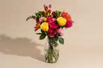 A bouquet of pink, orange, and yellow flowers resting in water in a clear jar.