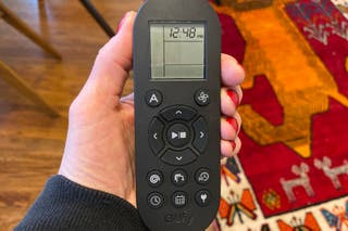 A person's hand holding the remote control for the Eufy RoboVac 11S Max robot vacuum.