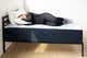 A person lying on their side on a foam mattress.