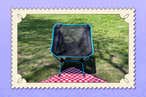 The Helinox One camping chair in the grass next to a picnic blanket.