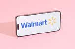 The Walmart logo on a smartphone lying horizontally on a pink background.