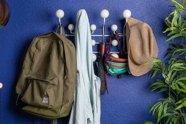 The eames coat rack with bags, hats and coats on it.